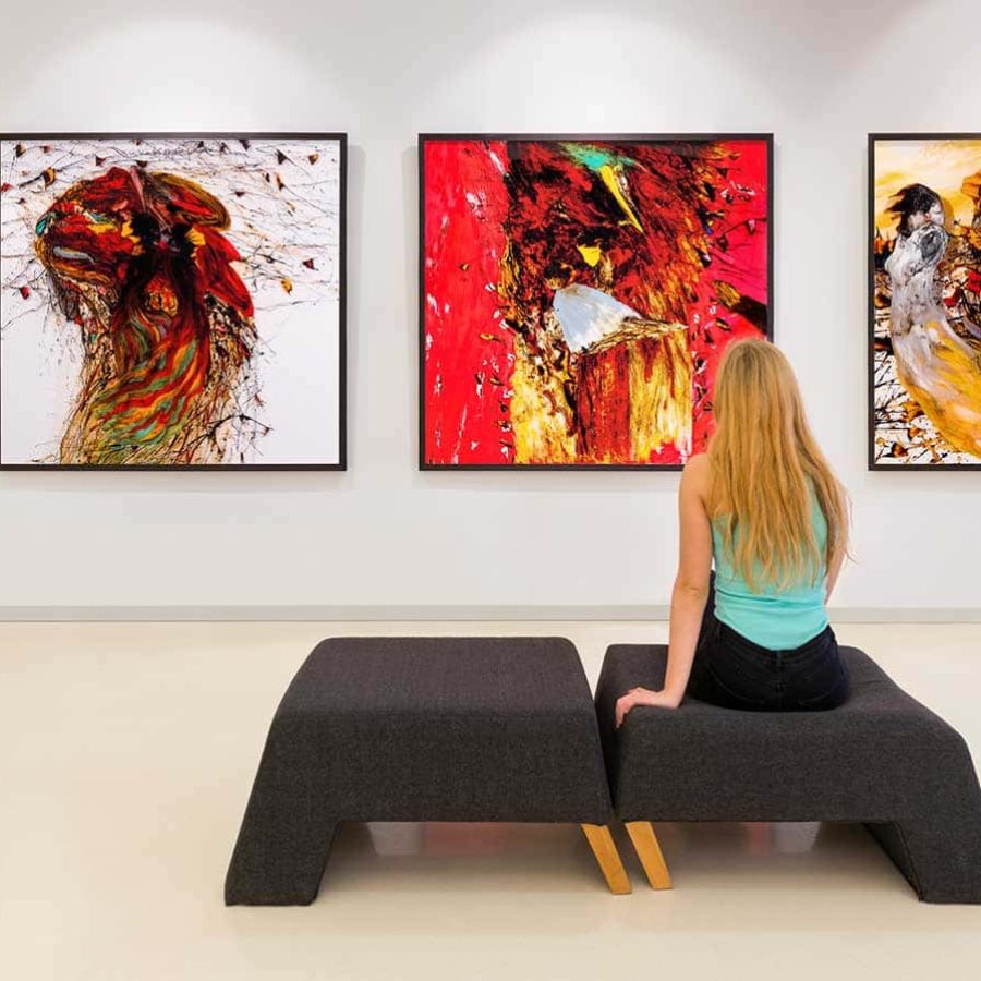 In a exhibition centre, lonely young woman visits an art exhibition and watches artist's collection on the wall. Exhibition's concept is "Angels"